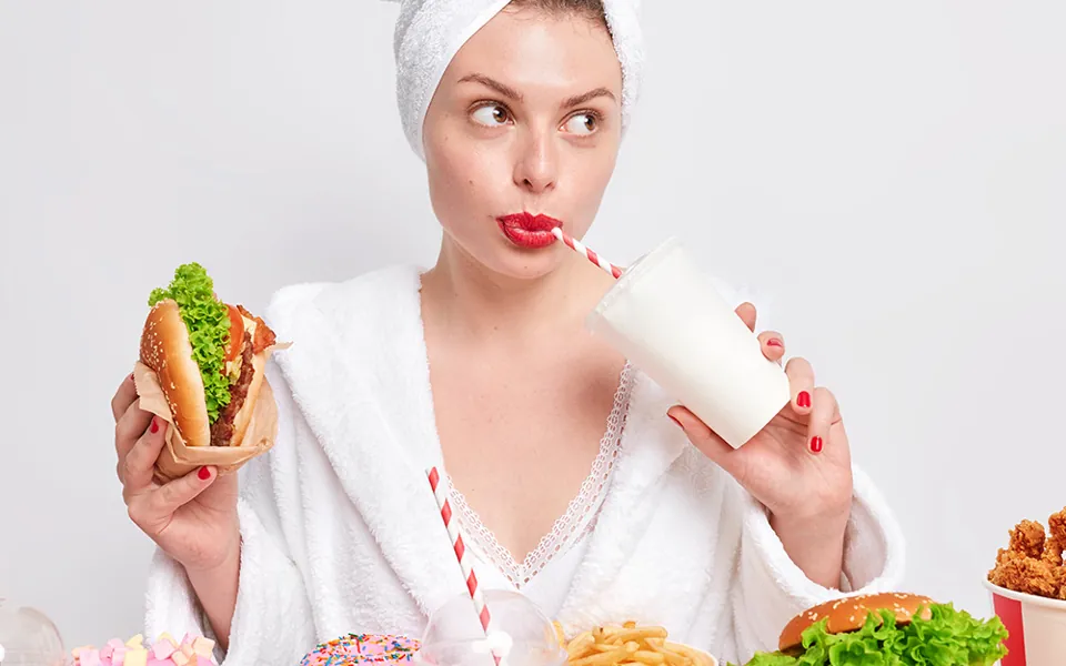 Mujer dudando ante una mesa llena de comida rápida