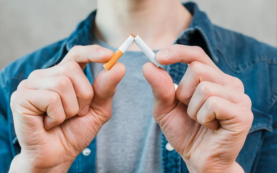 Manos partiendo un cigarrillo por la mitad