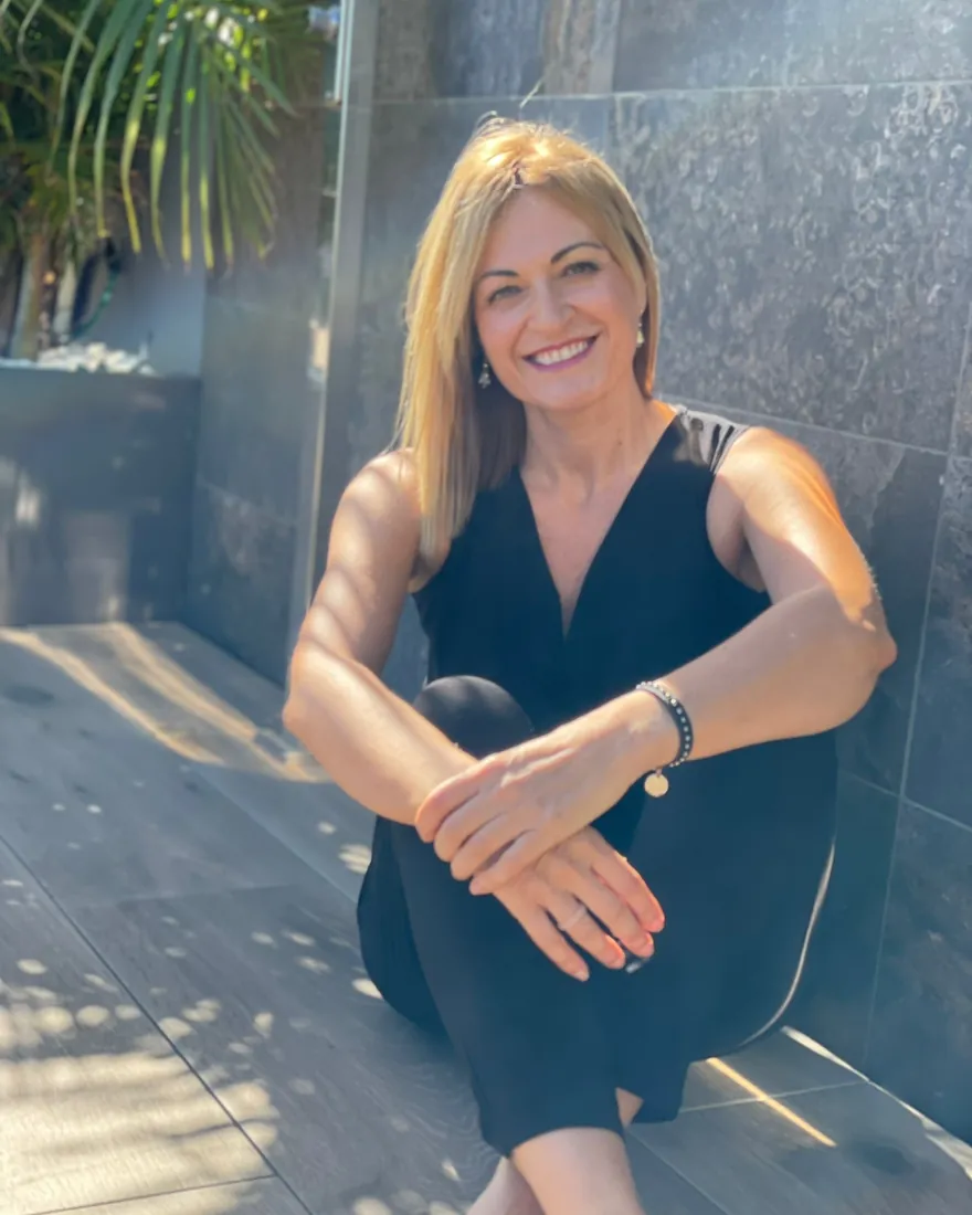 Eva Expósito, hipnoterapeuta y coach, sonriendo sentada en una terraza